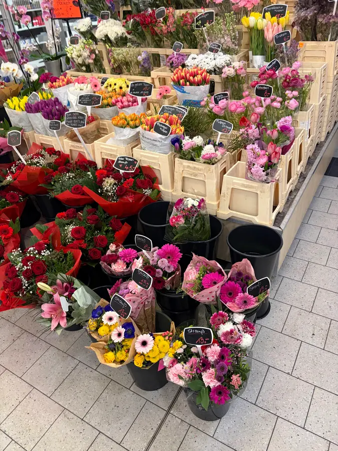 Blumenauswahl im Laden: Tulpen, Rosen, Gerbera und Chrysanthemen in Eimern und Kisten