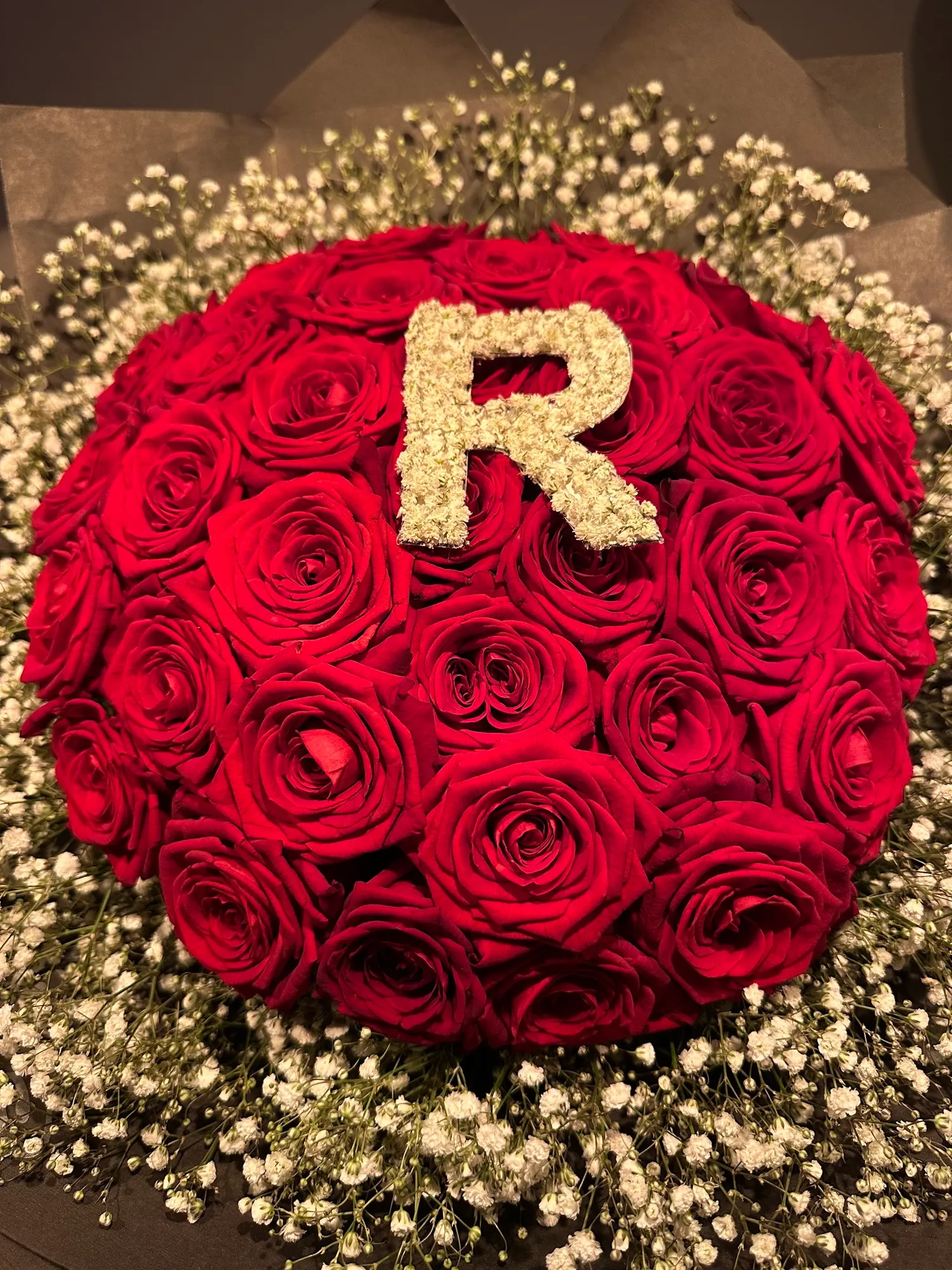 Kuppel aus roten Rosen mit Schleierkraut, in der Mitte ein „R“ aus Schleierkraut gebunden