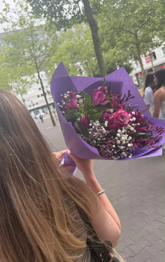 Strauß mit Rosen und Schleierkraut in lila Papier, draußen getragen