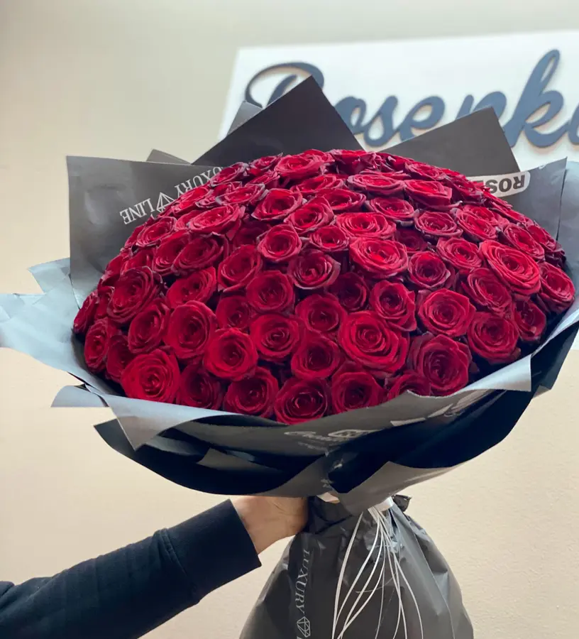 Riesiger Strauß aus roten Rosen in grauem Papier vor dem Rosenkavalier-Schriftzug